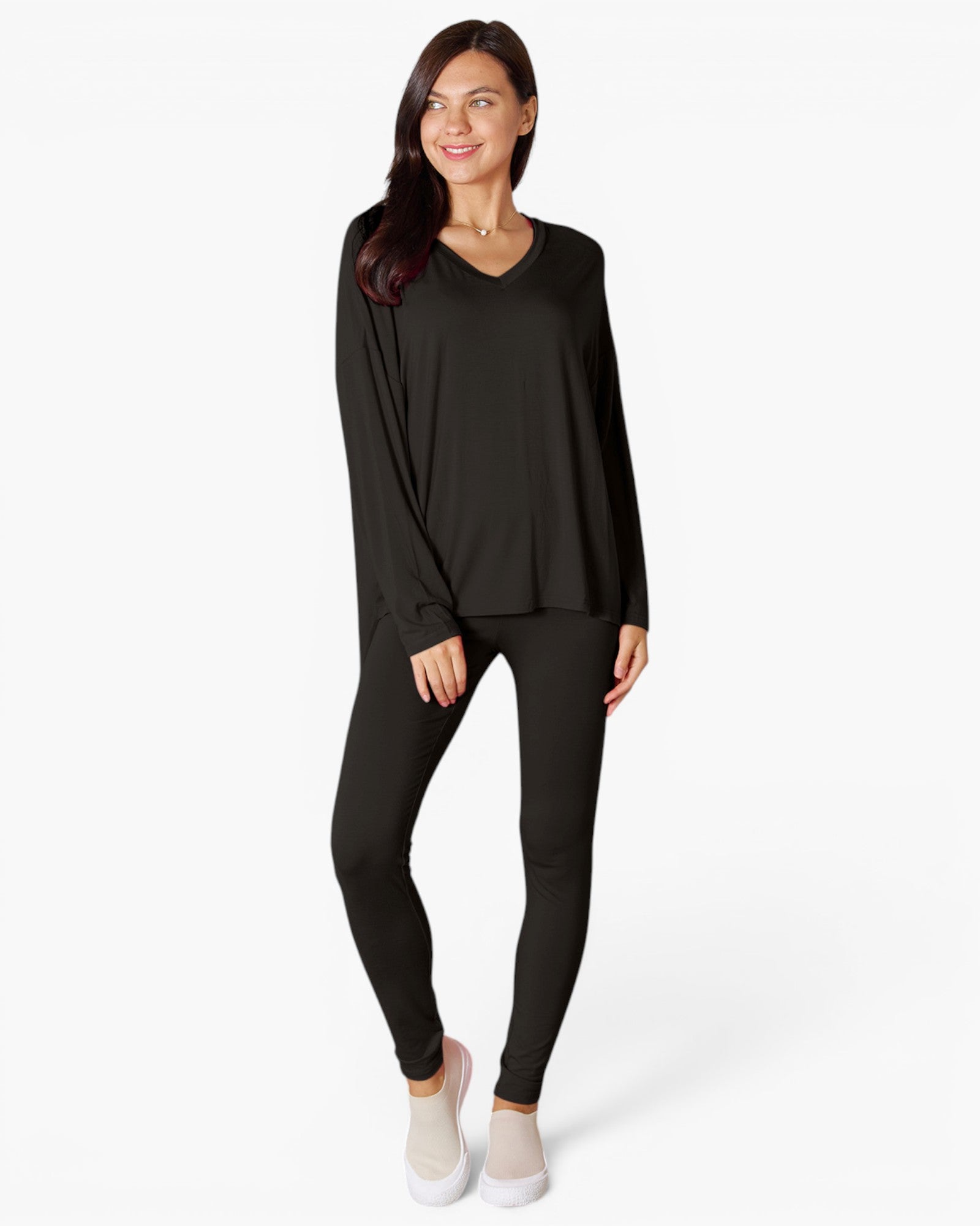 A woman modeling a black long-sleeve V-neck top and matching black leggings against a plain white studio background.