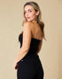 Woman wearing a black strapless top and high-waisted pants against a beige background