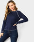 Woman wearing a navy blue sweater with white trim on a white background
