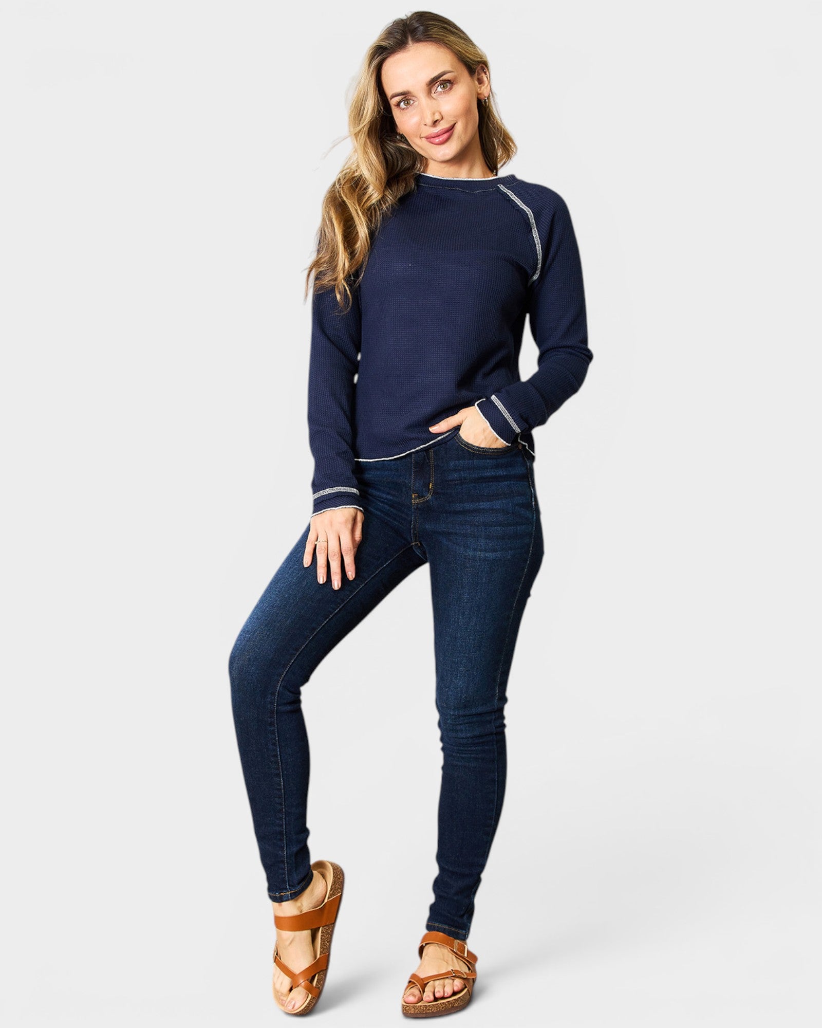 Woman wearing a navy blue sweater and jeans on a white background