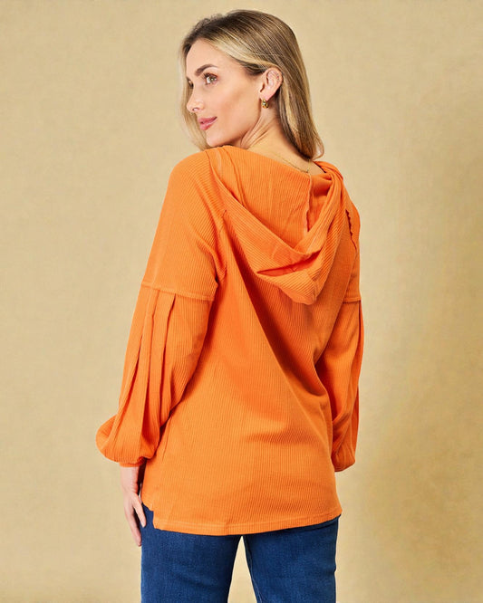 Woman wearing an orange corduroy jacket against a beige background