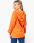 A woman wearing a bright orange hooded long-sleeve top, shown from the back against a plain white studio background.