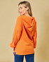Woman wearing an orange corduroy jacket against a beige background