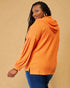 Woman wearing an orange hooded jacket against a beige background