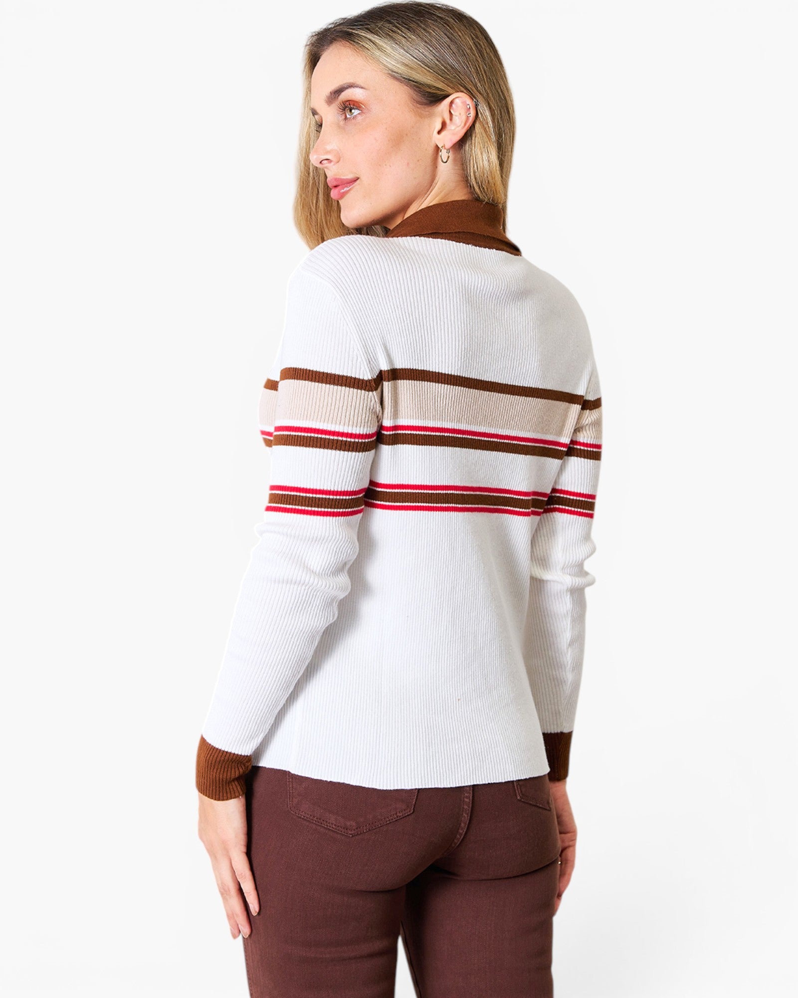 A woman shown from the back wearing a white ribbed knit sweater with brown and red horizontal stripes across the shoulders and sleeves, paired with brown pants, against a plain white background.