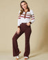 Woman wearing a striped sweater and brown pants against a beige background