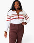 A woman modeling a white ribbed knit polo sweater with brown and red stripes, paired with brown pants, against a plain white background.