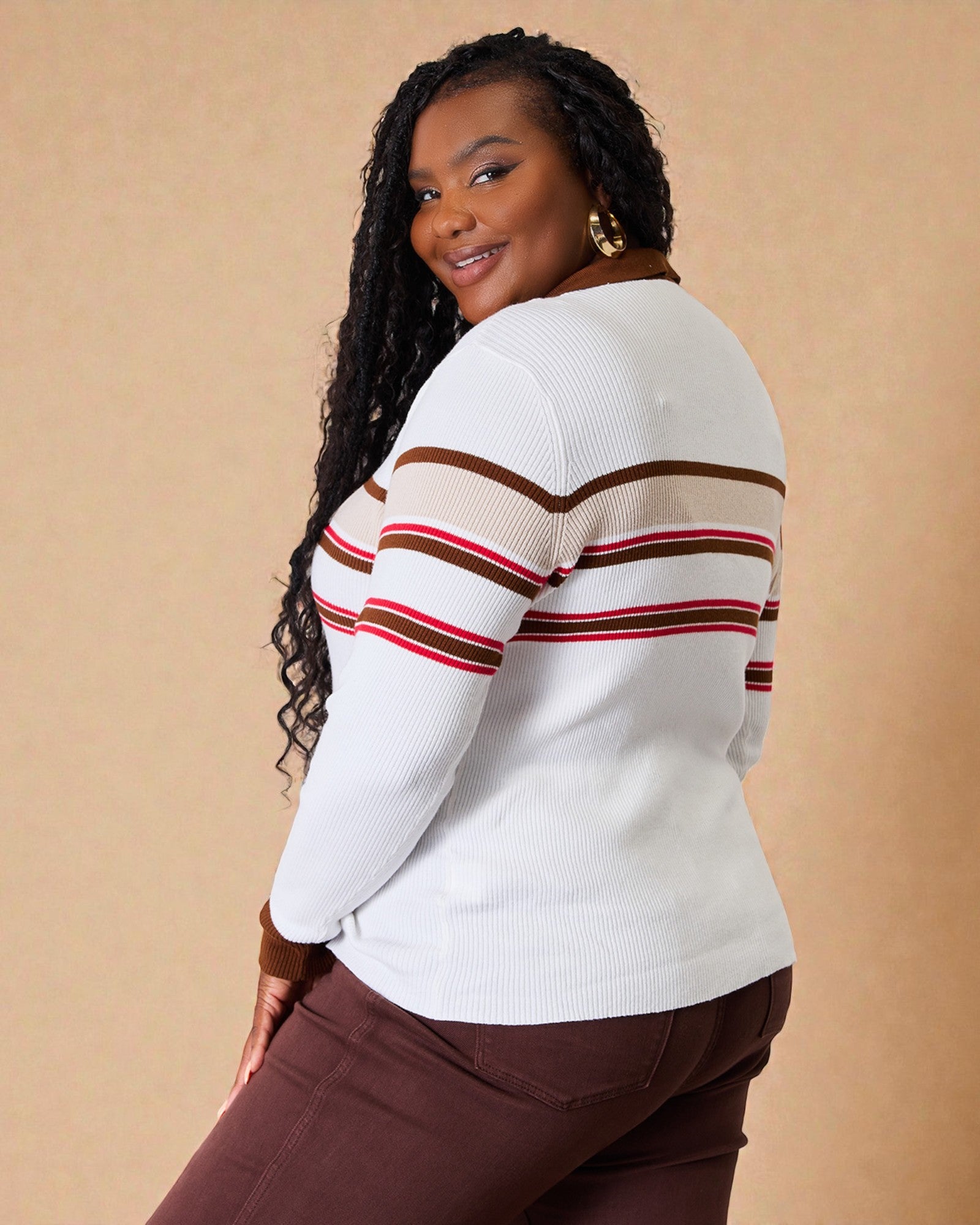 Woman wearing a white sweater with brown and red stripes on a beige background