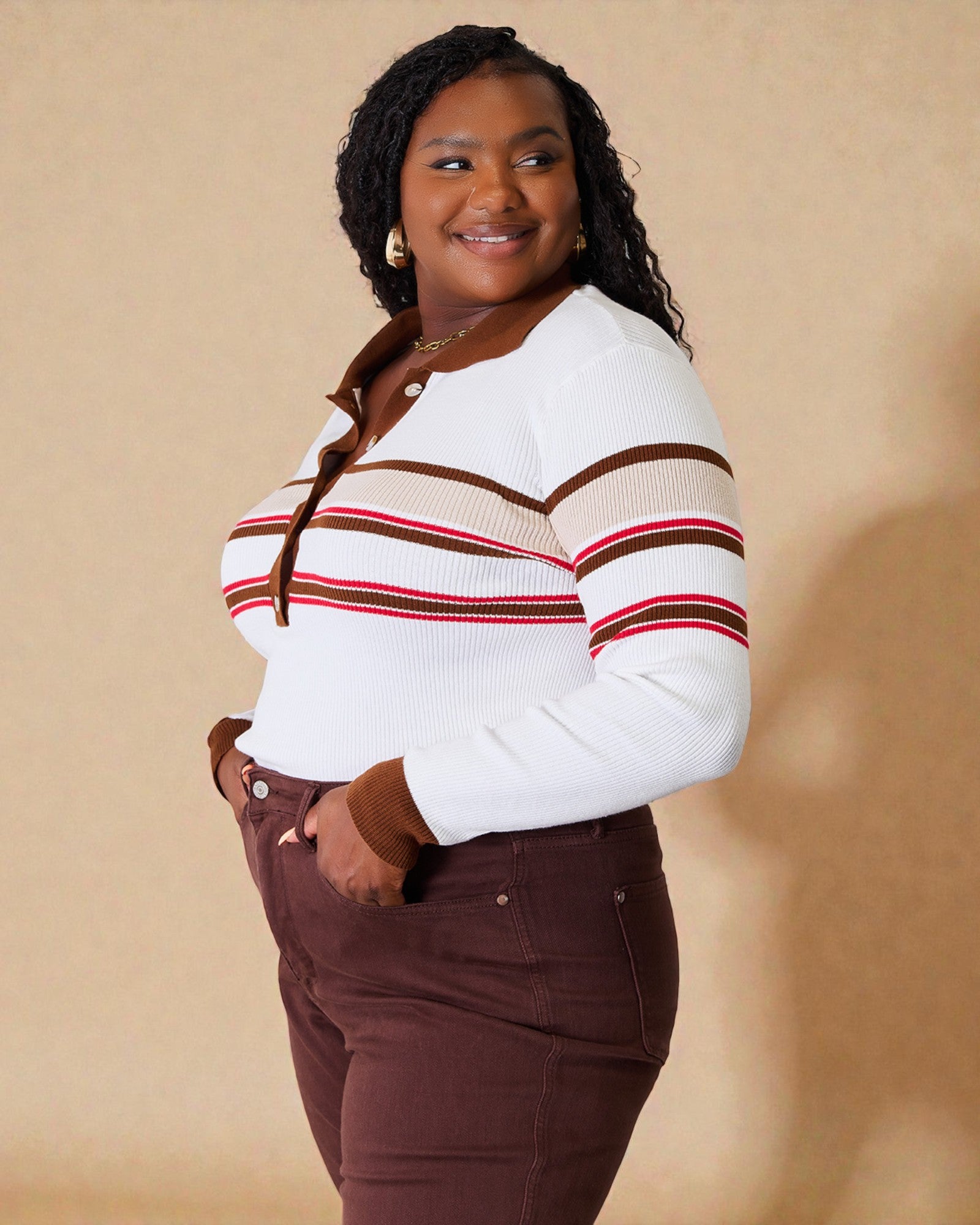 Woman wearing a white sweater with red and brown stripes against a beige background
