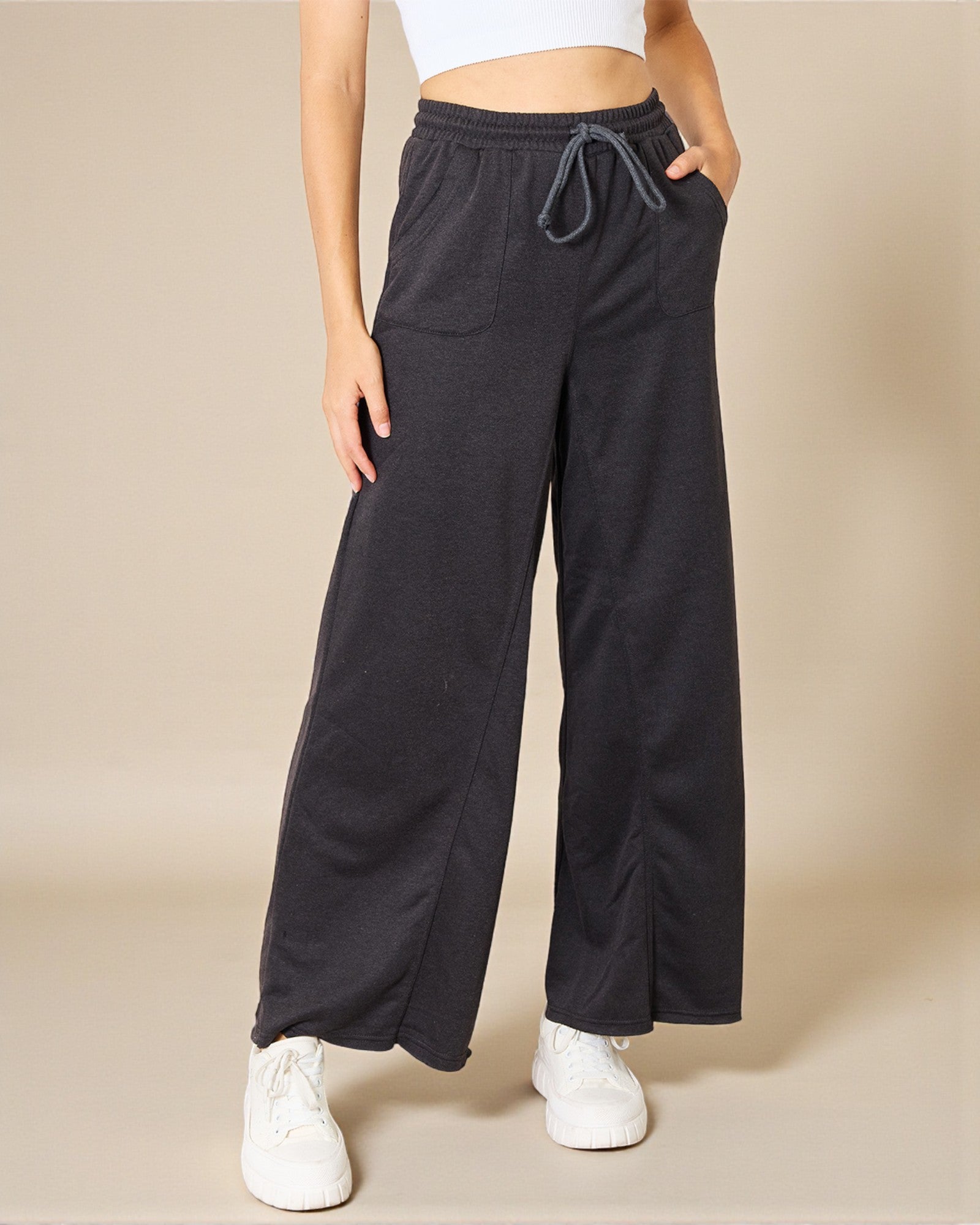 Person wearing black wide-leg pants with a beige background