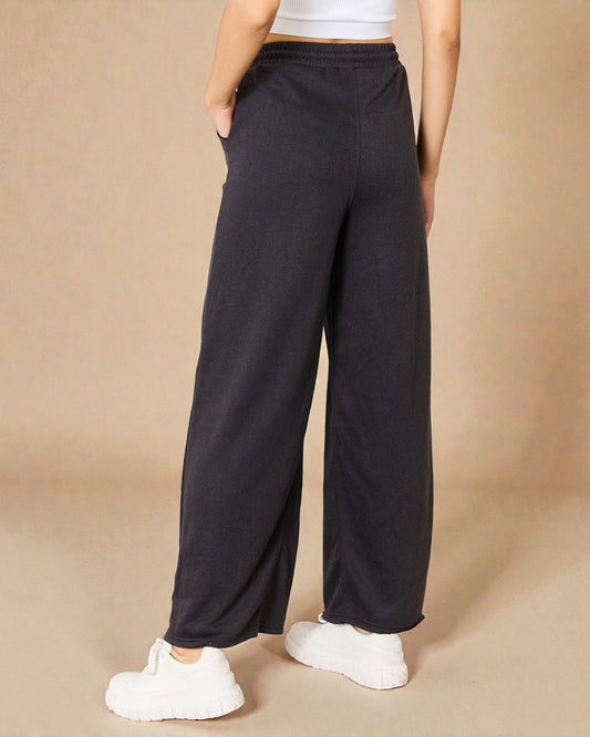 Person wearing black wide-leg pants on a beige background