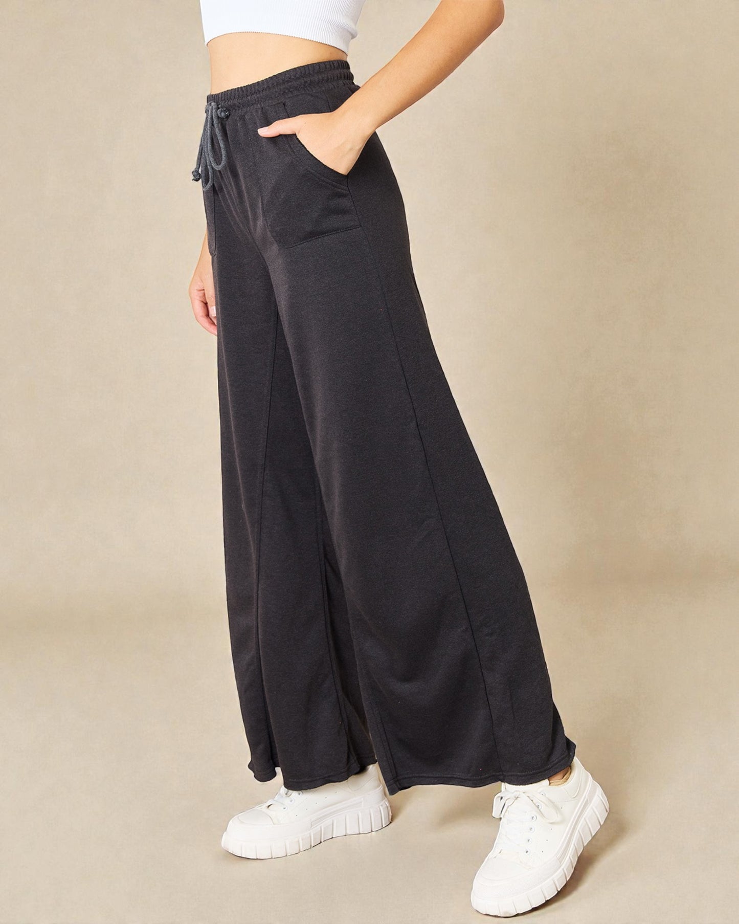 Person wearing black wide-leg pants with a beige background