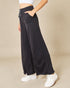 Person wearing black wide-leg pants with a beige background