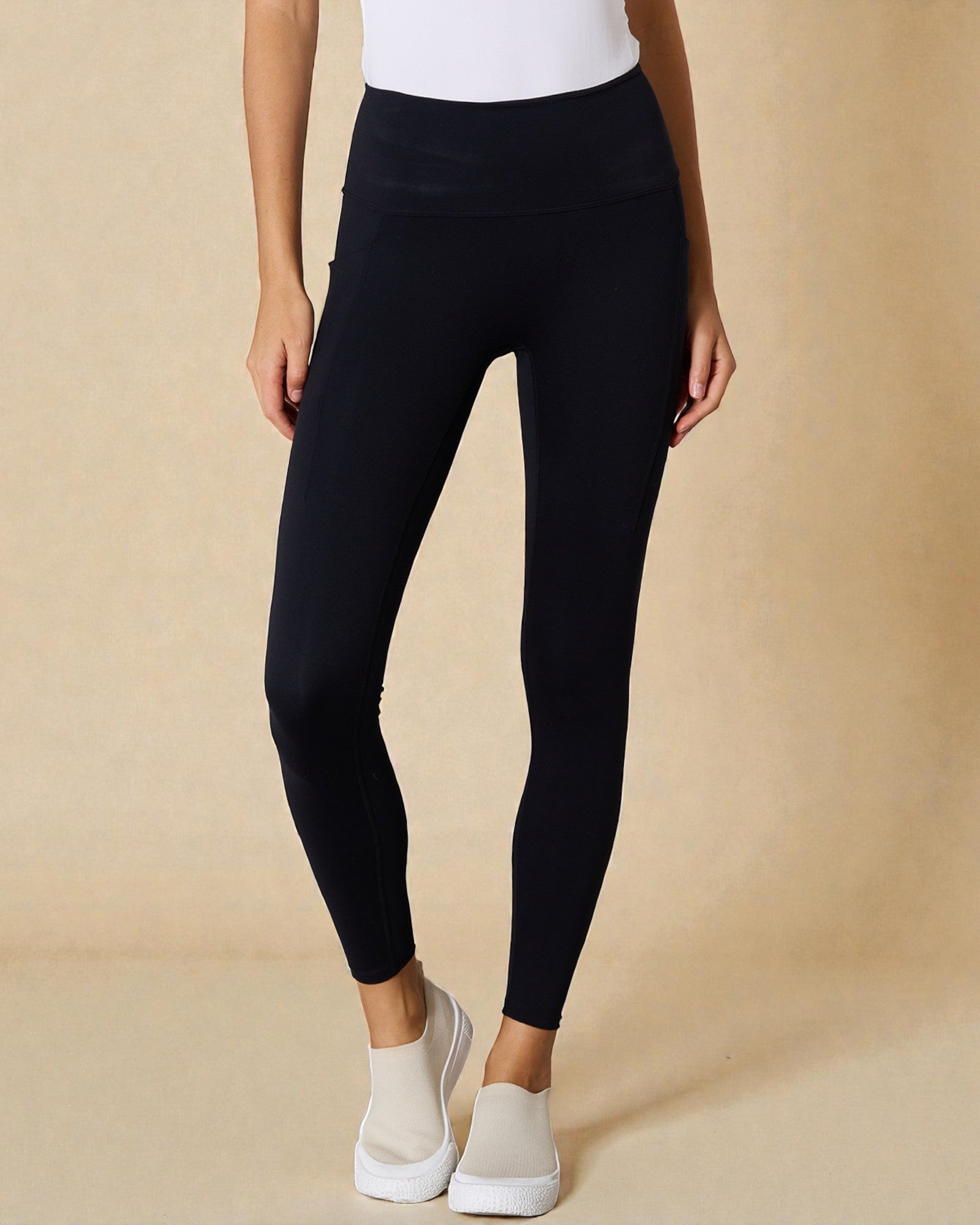 Person wearing black leggings with a beige background