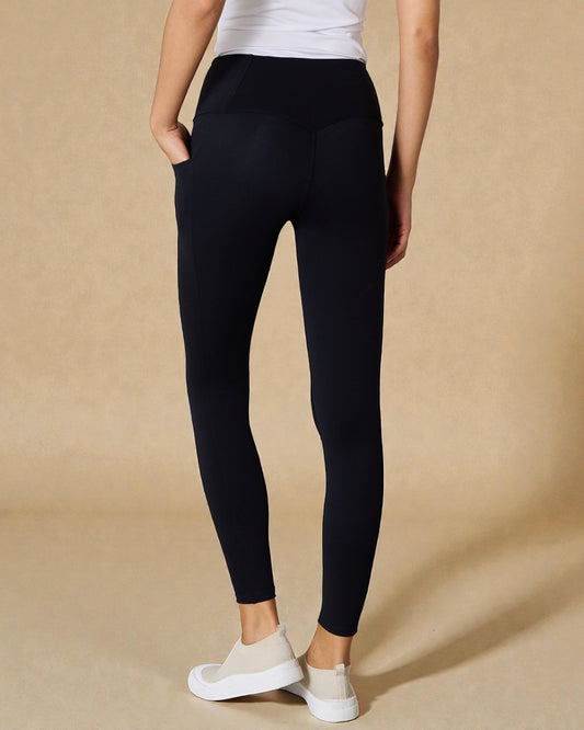 Person wearing black leggings on a beige background