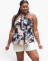 A woman modeling a black halter-neck tank top with a colorful floral print in pink, orange, and white, paired with white shorts, against a plain white background.
