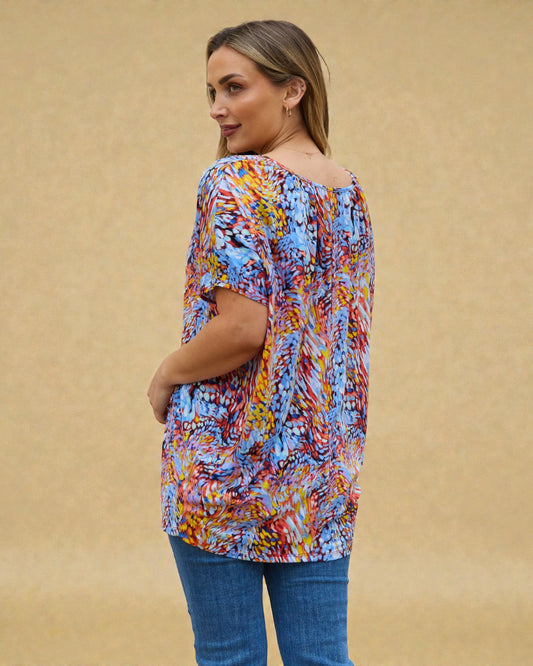 Woman wearing a colorful patterned top against a beige background