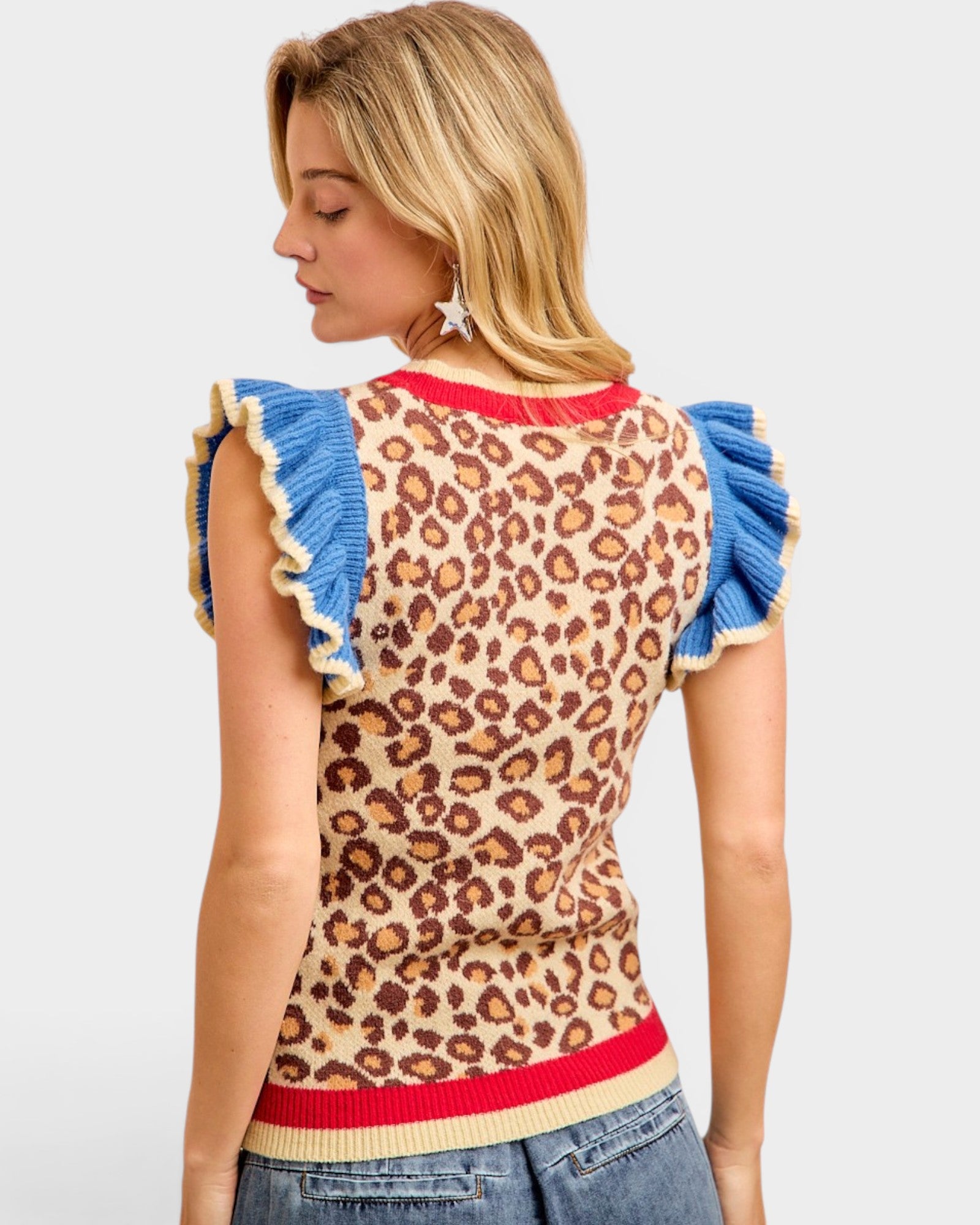 Woman wearing a leopard print top with blue ruffled sleeves on a white background
