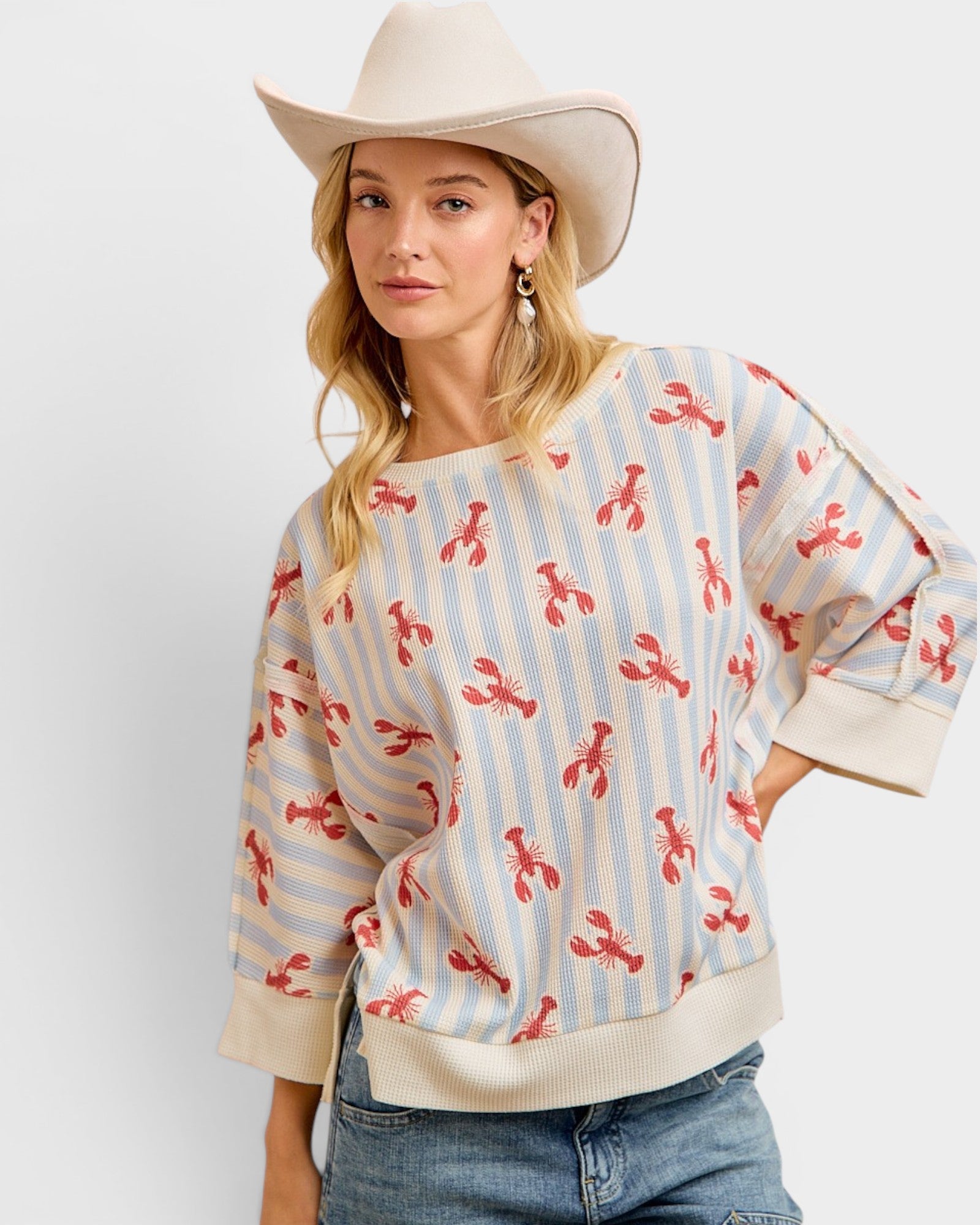 Woman wearing a sweater with lobster pattern and cowboy hat on a white background