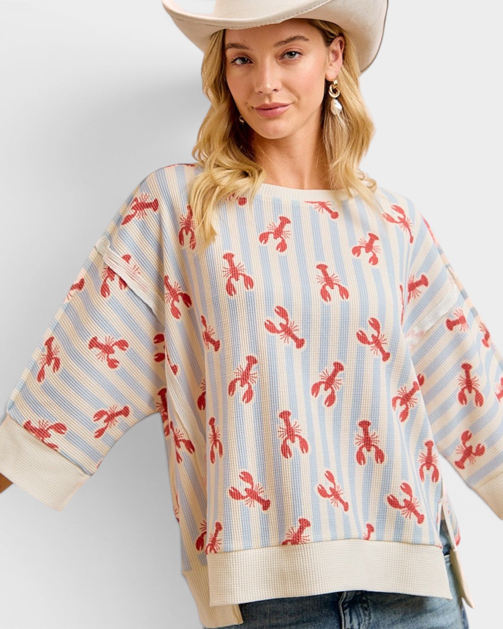 Woman wearing a sweater with lobster pattern and a cowboy hat on a white background