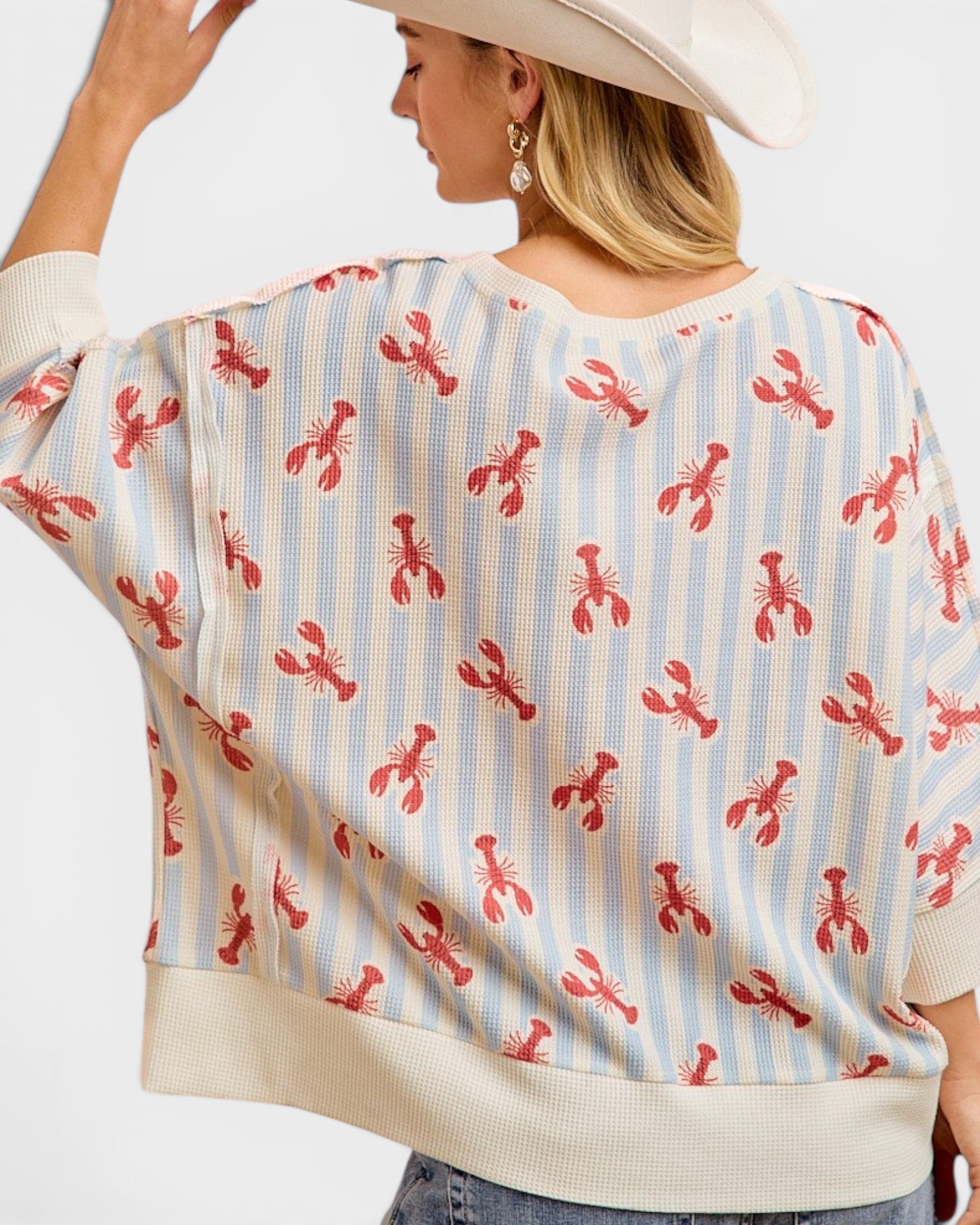 Person wearing a sweater with red lobster pattern on a white background