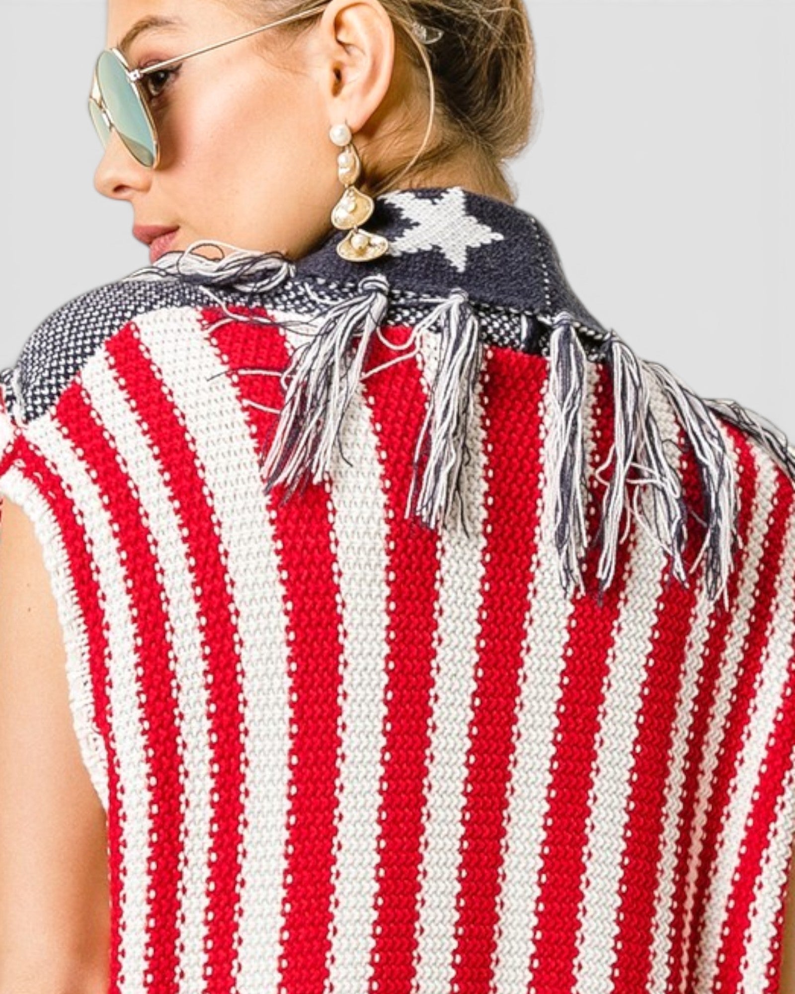 Person wearing a red, white, and blue striped sleeveless top with fringe details.