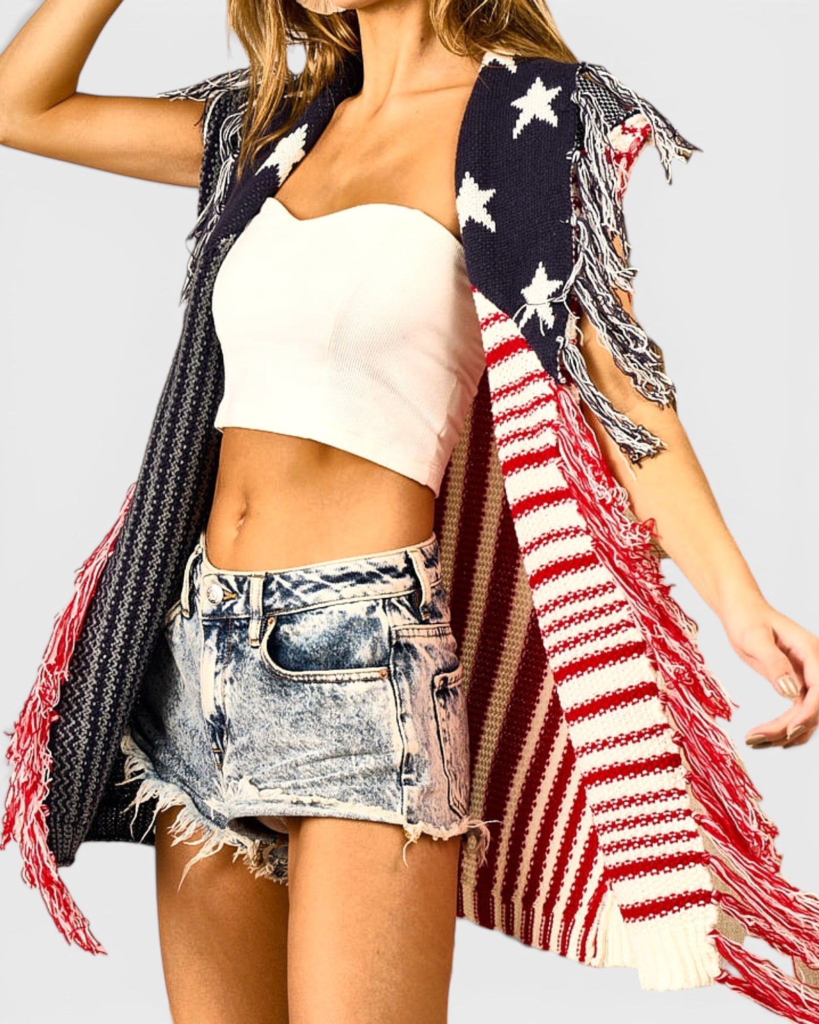 Person wearing a sleeveless top, denim shorts, and an American flag shawl on a light gray background