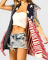 Person wearing a sleeveless top, denim shorts, and an American flag shawl on a light gray background