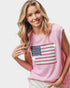 Woman wearing a pink sleeveless top with an American flag design on a plain background