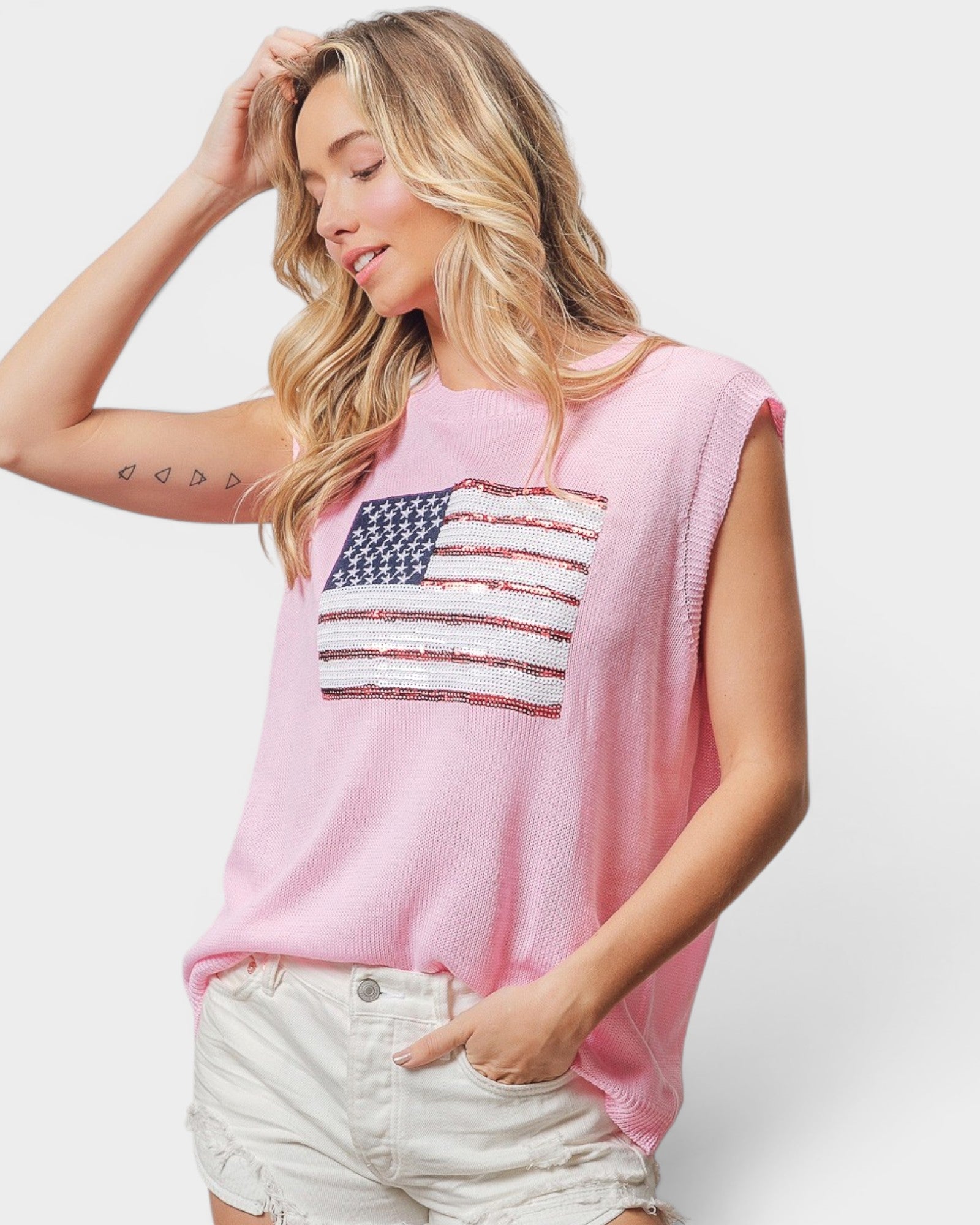 Woman wearing a pink sleeveless top with an American flag design on a white background