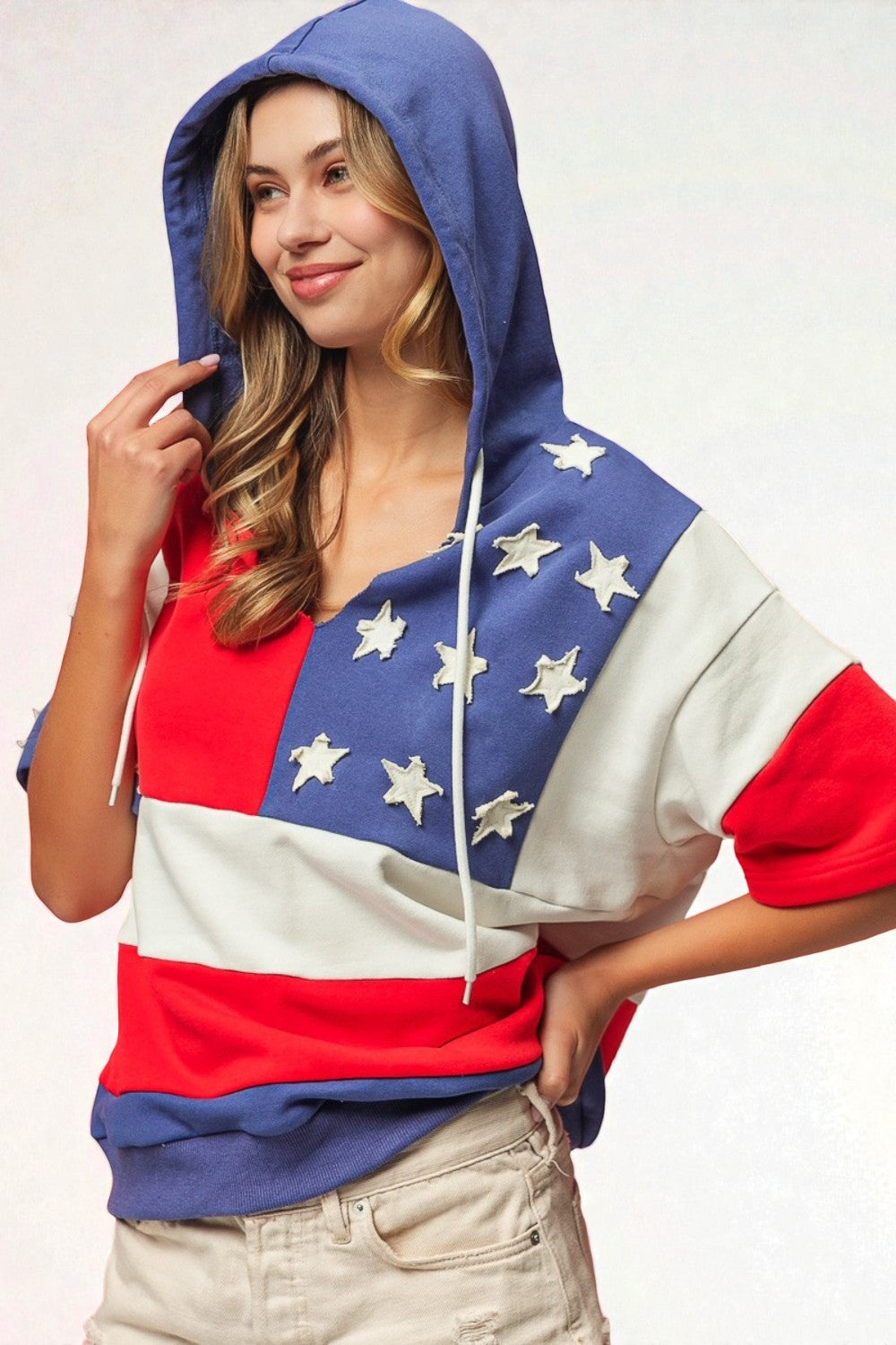 Person wearing a hoodie with an American flag design on a plain background