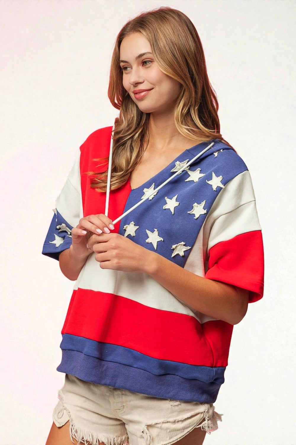 Woman wearing a colorful flag-themed top on a white background