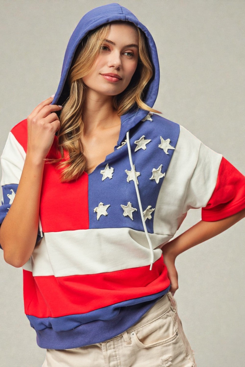 Woman wearing a hoodie with an American flag design on a plain background