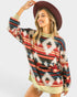 Woman wearing a colorful patterned sweater and red hat on a white background
