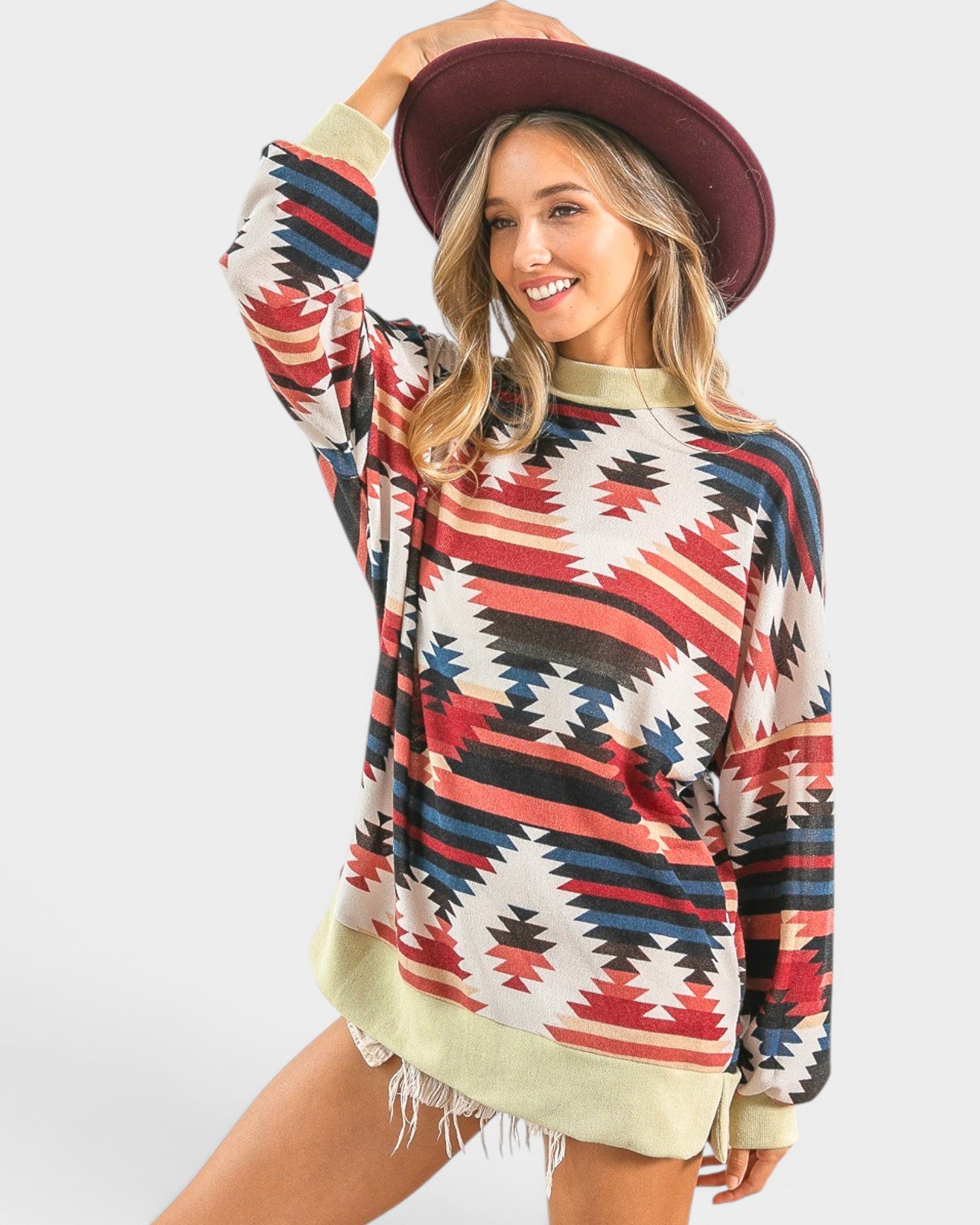 Woman wearing a colorful patterned sweater and maroon hat on a white background