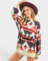 Woman wearing a colorful patterned sweater and maroon hat on a white background