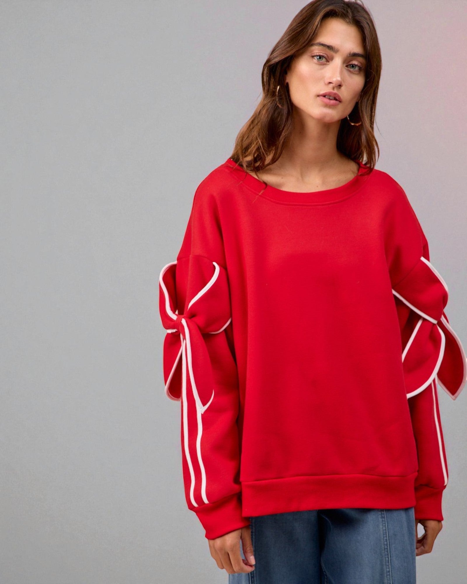 Person wearing a red sweatshirt with white accents on a gray background