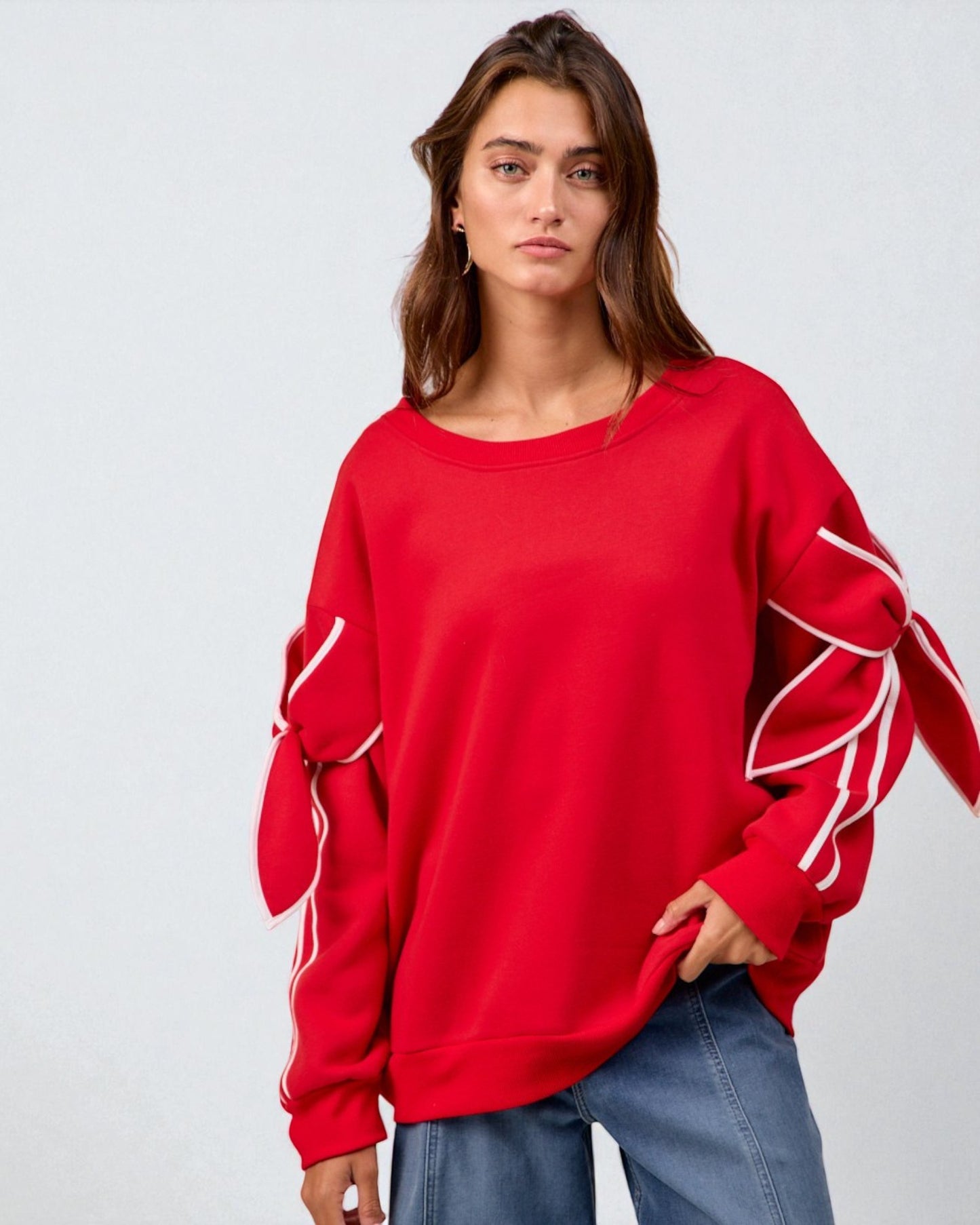 Woman wearing a red sweatshirt with white accents on a plain background