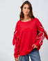 Woman wearing a red sweatshirt with white accents on a plain background