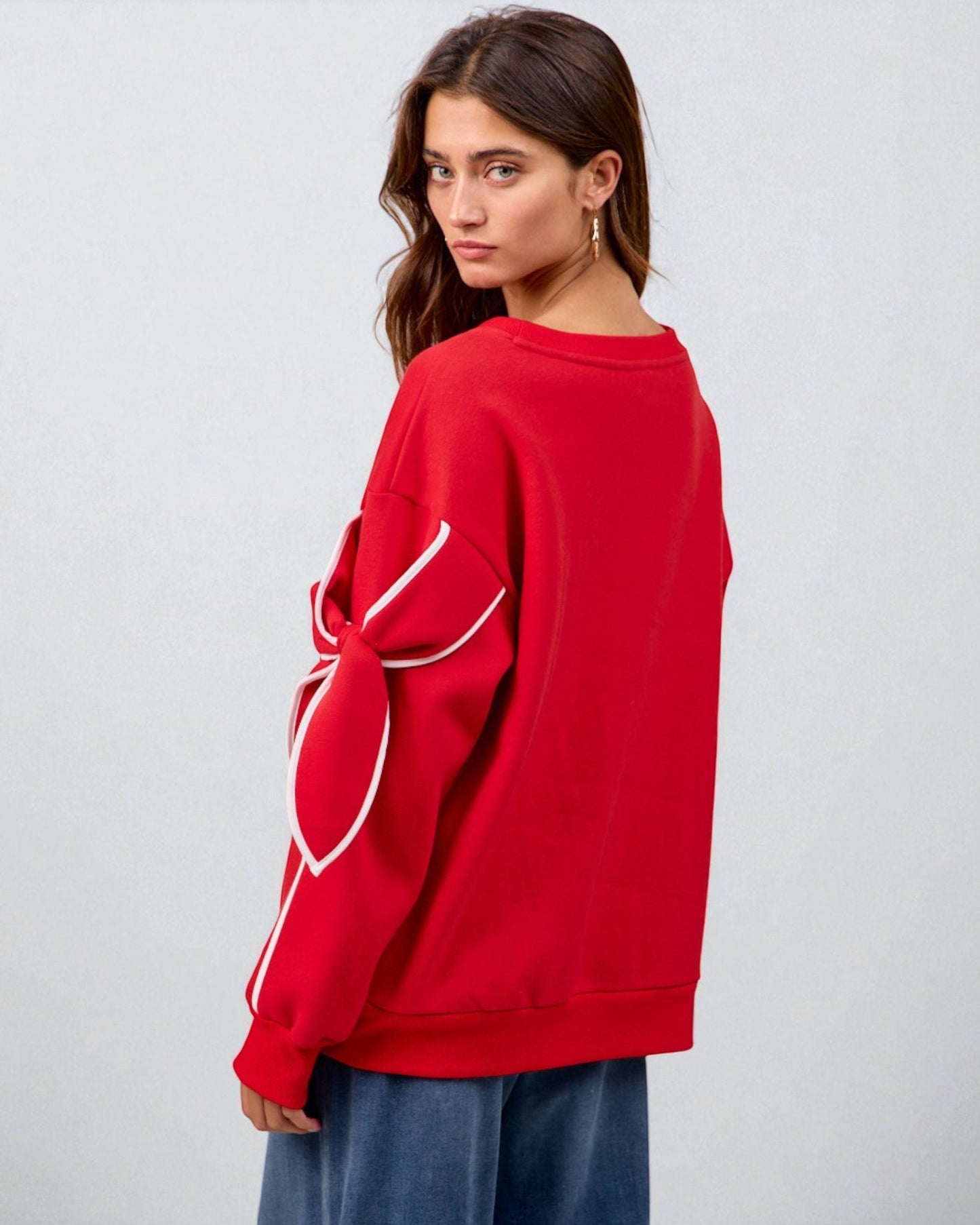 Person wearing a red sweatshirt with a white heart design on a plain background