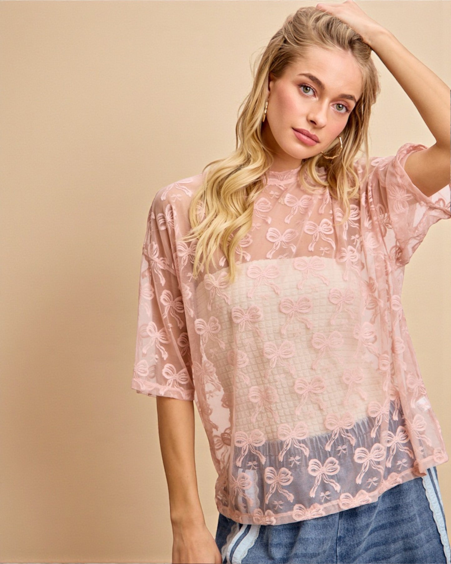 Woman wearing a pink lace top with a beige background