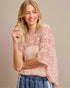 Woman wearing a pink lace top with a beige background