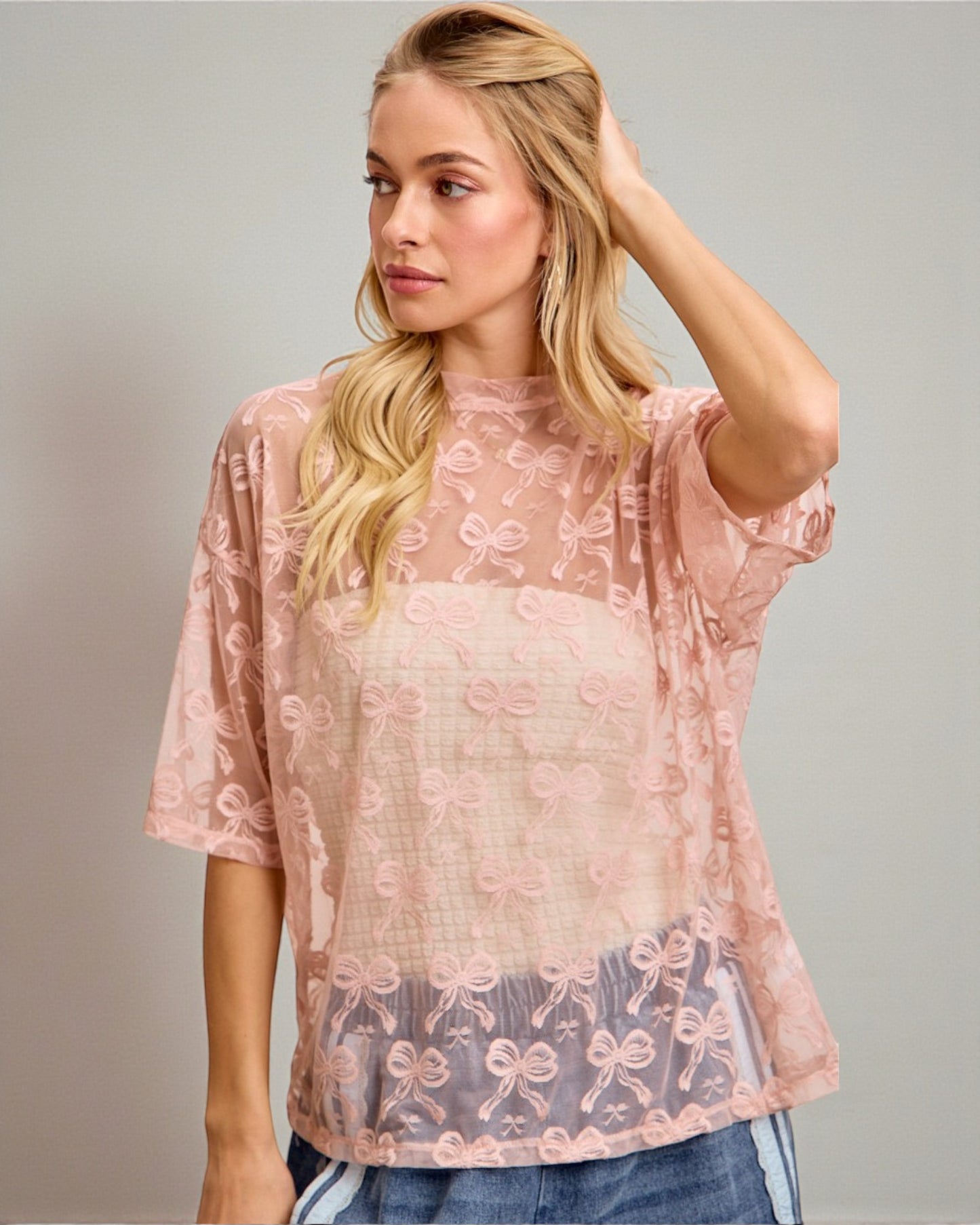 Woman wearing a pink lace top against a gray background