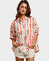 Woman wearing a white shirt with red patterns and white shorts on a plain background