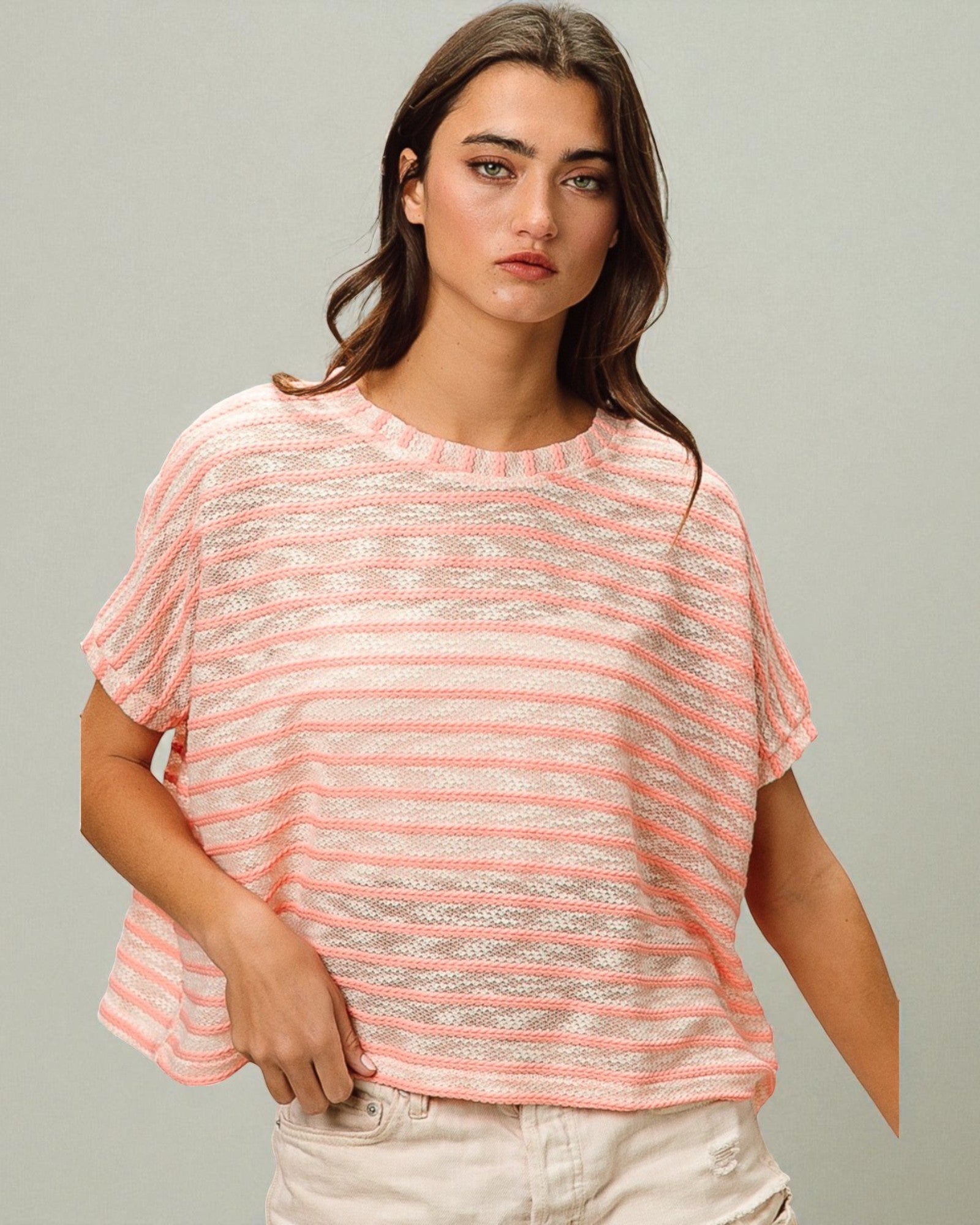 Woman wearing a pink and white striped shirt against a gray background