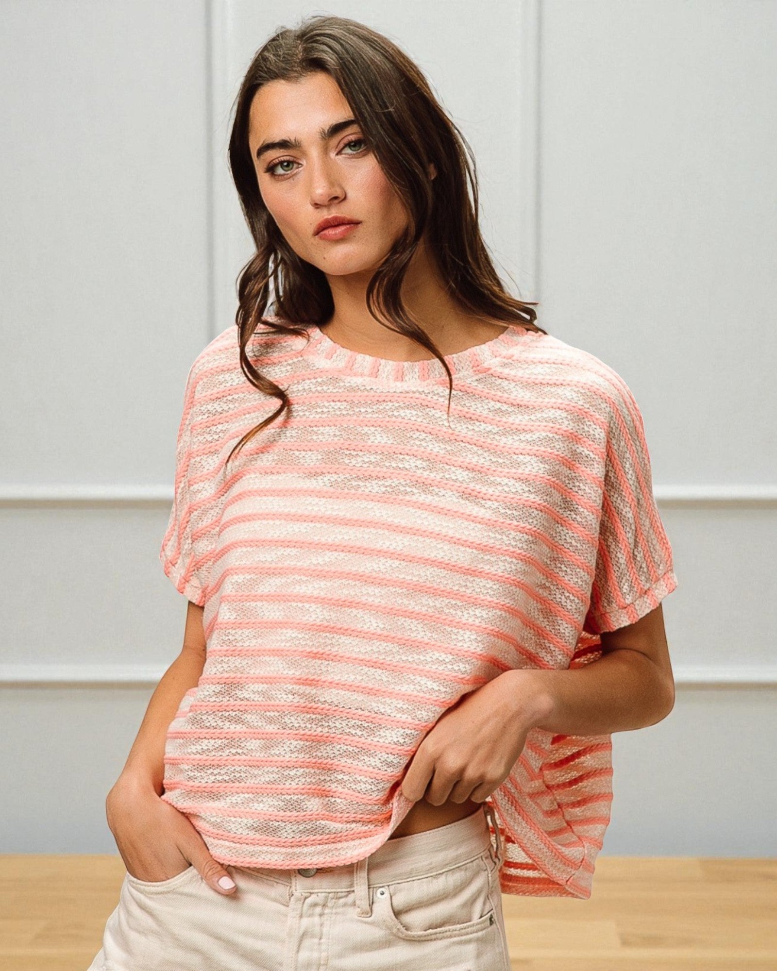 Woman wearing a pink and white striped shirt against a neutral background