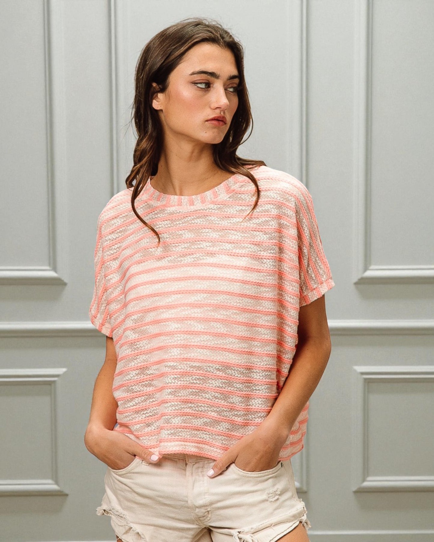 Woman wearing a pink striped shirt against a gray paneled wall