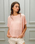 Woman wearing a pink striped shirt against a gray paneled wall
