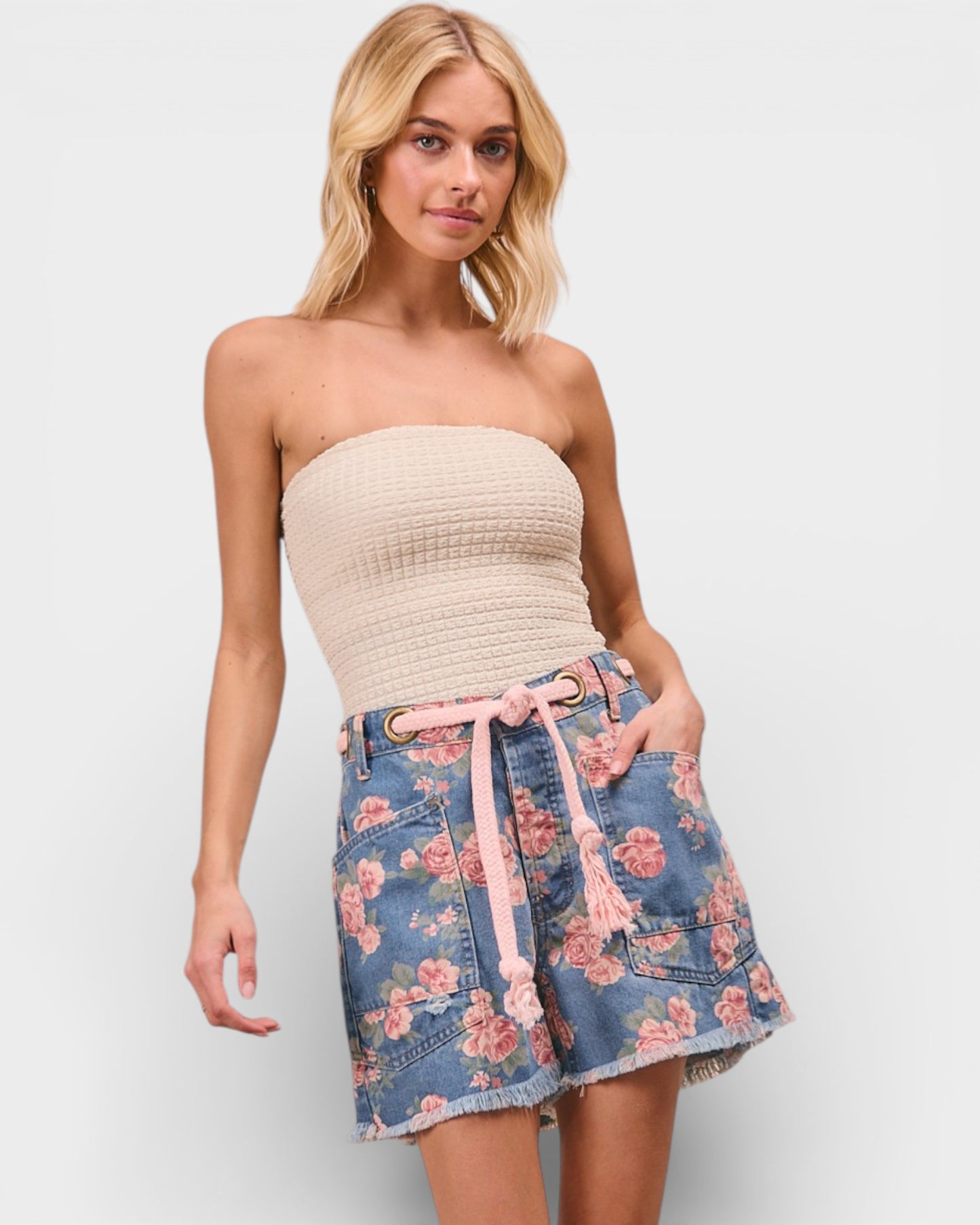 Woman wearing a strapless beige top and floral denim skirt on a plain background