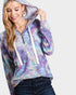 Woman wearing a tie-dye hoodie with a white zipper on a plain background
